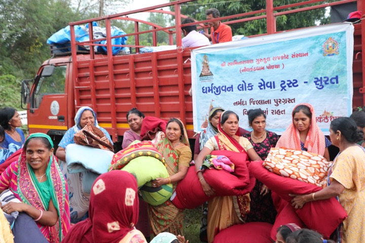 Women seated near the service truck with bedding and support supplies